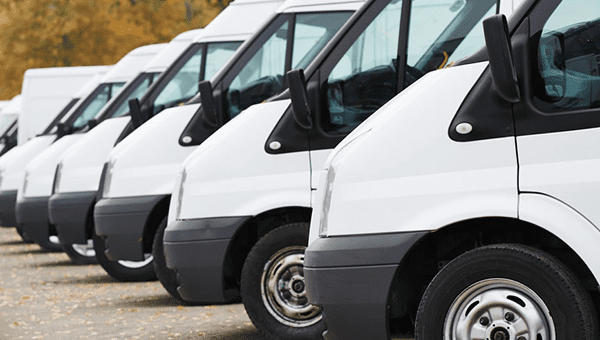 nine white vans parked in a row in a parking lot