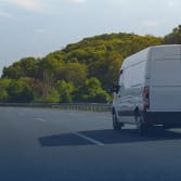 Sprinter van on open road with trees and forest surrounding it