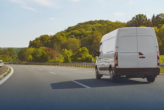 Sprinter van on open road with trees and forest surrounding it