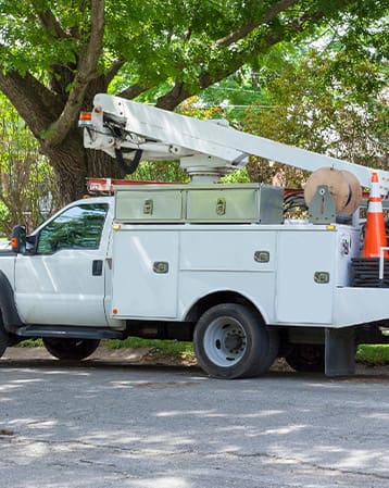 A white boom truck equipped with a person carrying bucket and storrage compartment upfits