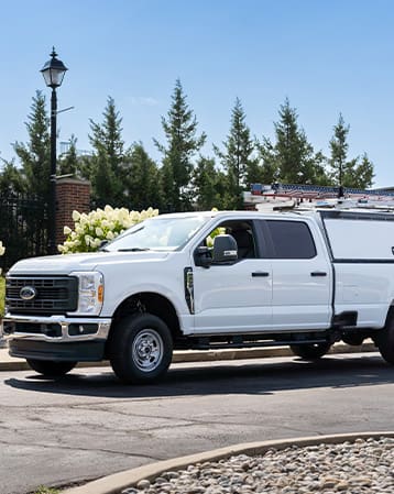 White pickup truck outside of a building with ladder racks and cap storage compartments