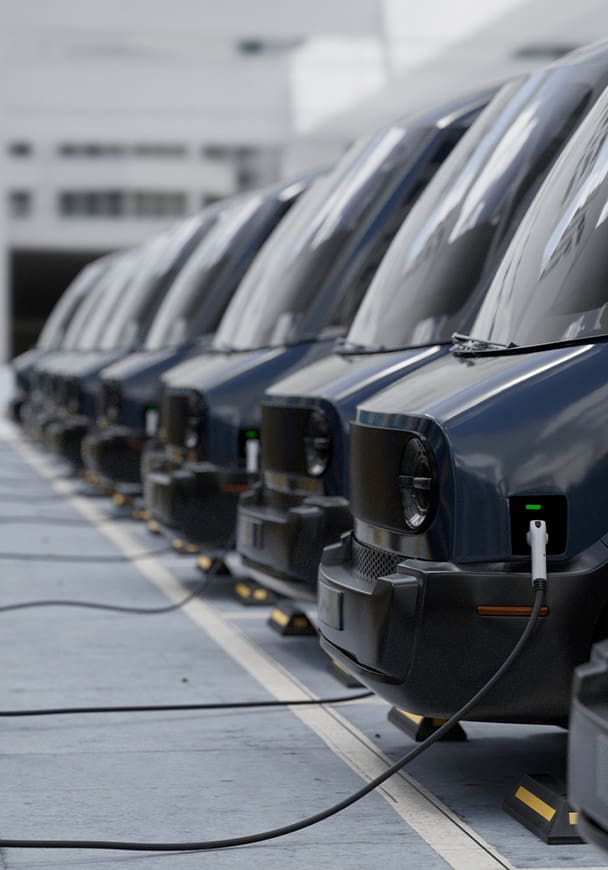 A fleet of electric vans charging in a parking area