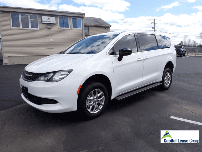 Wheelchair accessible mini van white with wheelchair ramp in rear of the van. Ramp is up and gate is closed. Driver's side view. Chrysler Voyageur